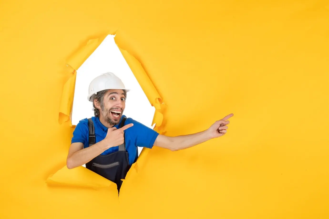 Front view of a male builder in uniform on a yellow-colored desk; constructor, building, architecture, job, structure, worker.