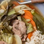 A bowl of Sinigang with pork, vegetables, and tamarind